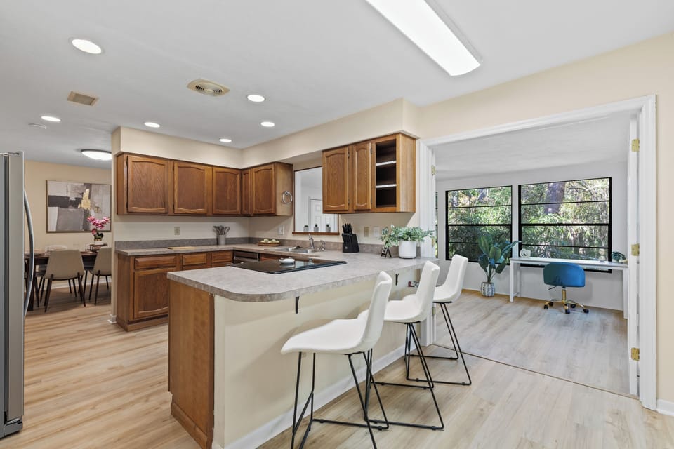 Kitchen with wood cabinets, island bar seating & view into home office