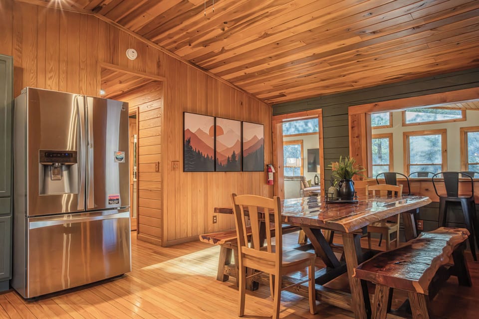 Live-edge dining table with bench seating, bar, and cozy rustic decor.