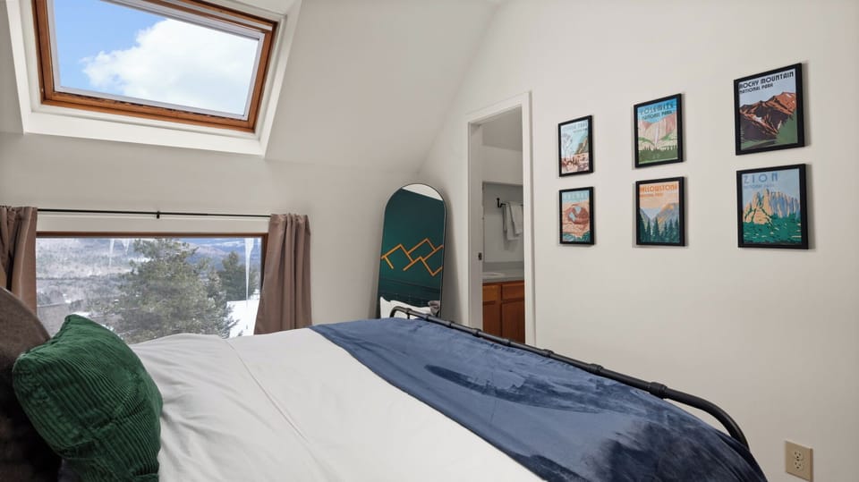 - Bedroom with skylight view of snowy mountains outside   - Stylish mountain wall art adds unique alpine charm   - Ensuite access with snowboarding decor accent
