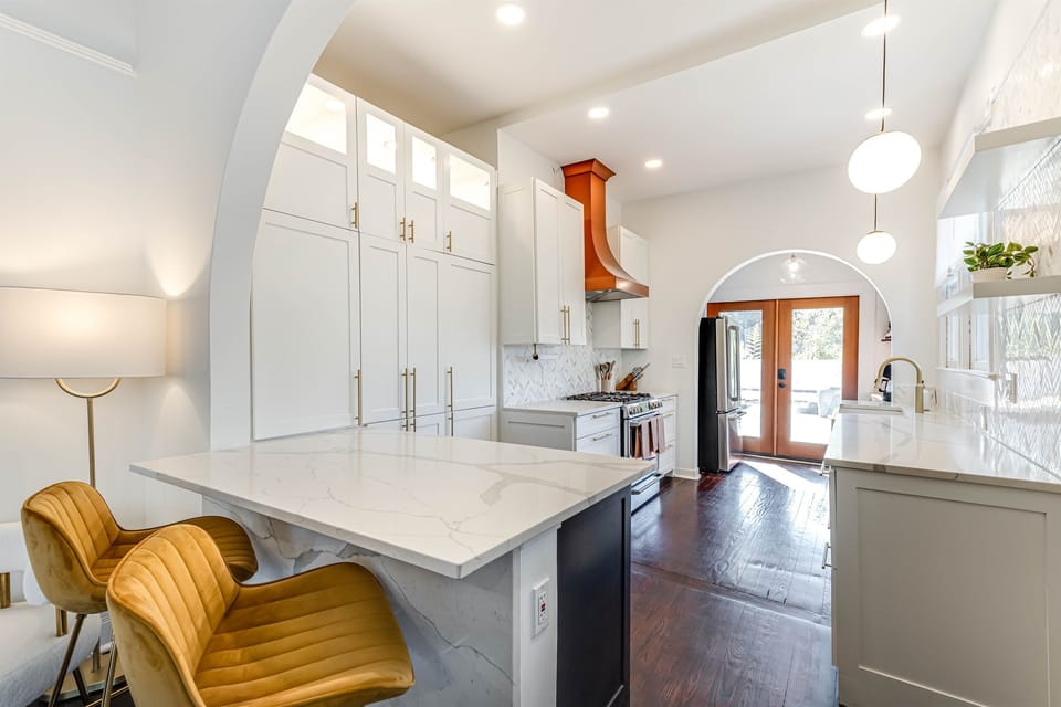 An elegant kitchen with stylish bar chairs, sleek countertops, and seamless access to the backyard, creating a perfect blend of modern design and functionality.