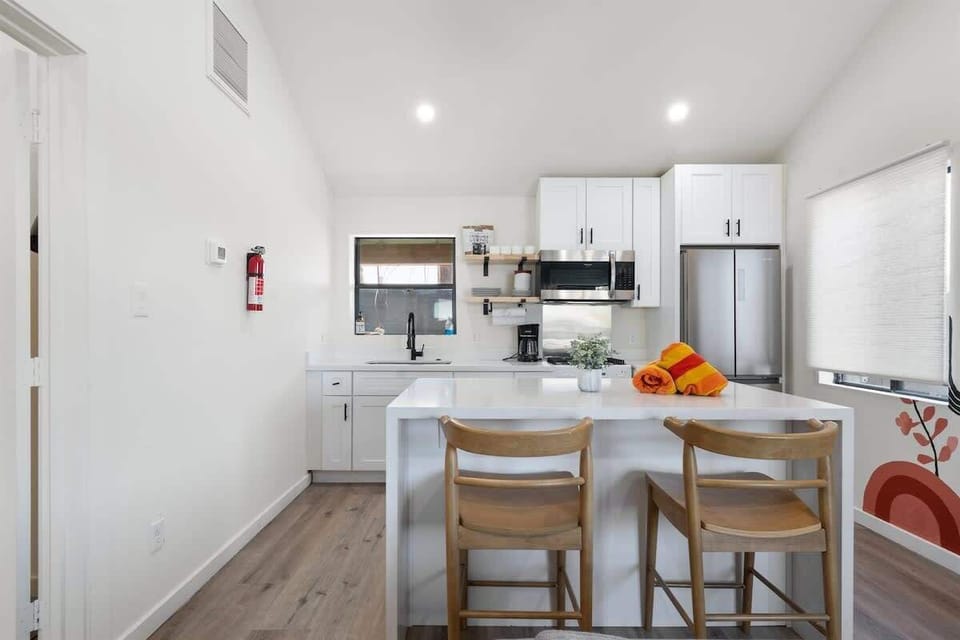Modern white kitchen with a clean island and bar seating—chop, plate, and keep the conversation going while everything stays bright and open.