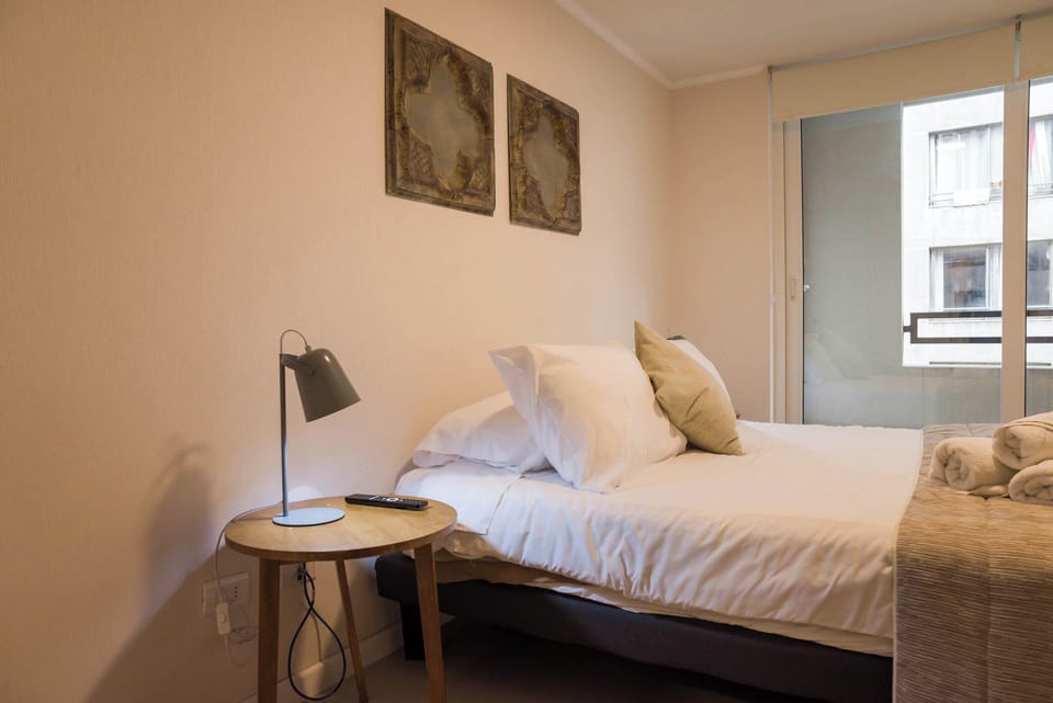 Relax in this cozy bedroom with modern decor and natural light, perfect for a restful stay.