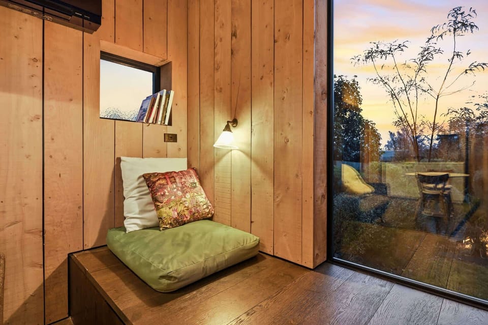 Window seat nook with a reading shelf and sunset through the glazing
