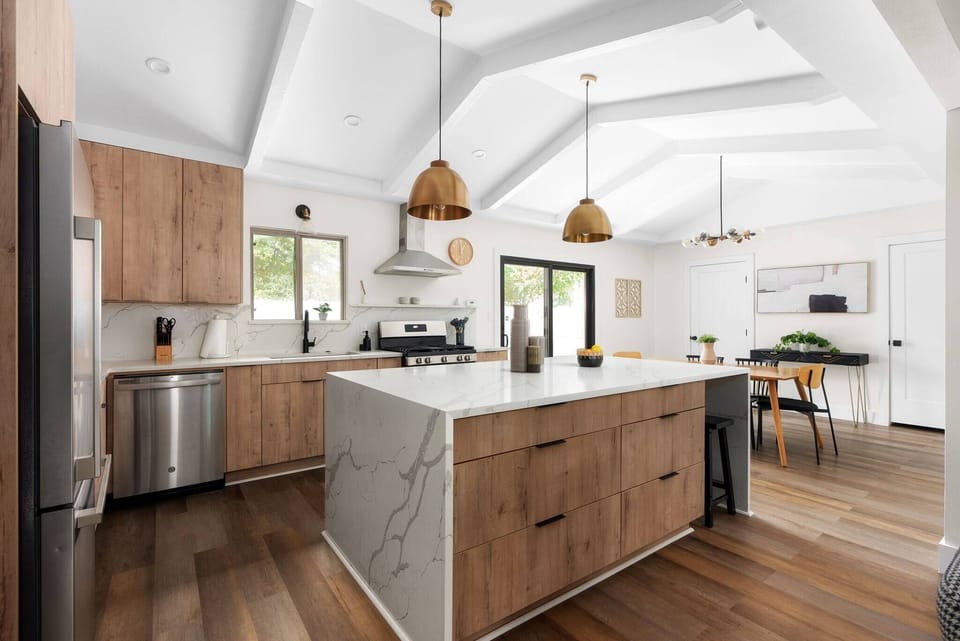 Cook and connect in a stunning kitchen with a large marble island, stainless steel appliances, and vaulted ceilings that make the space bright and airy