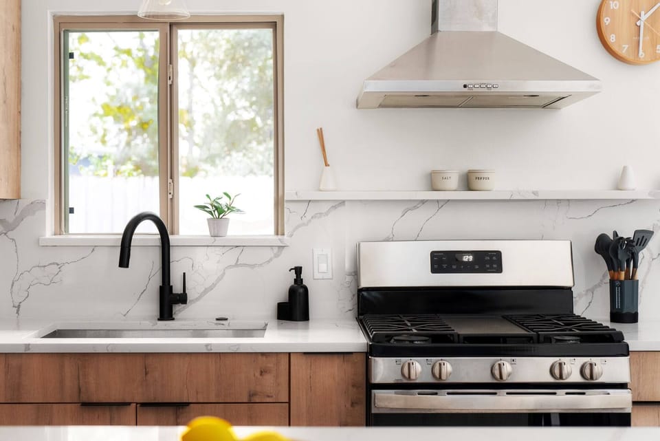 Sleek and functional kitchen with stainless steel gas range, marble backsplash, and everything you need to cook at home with ease