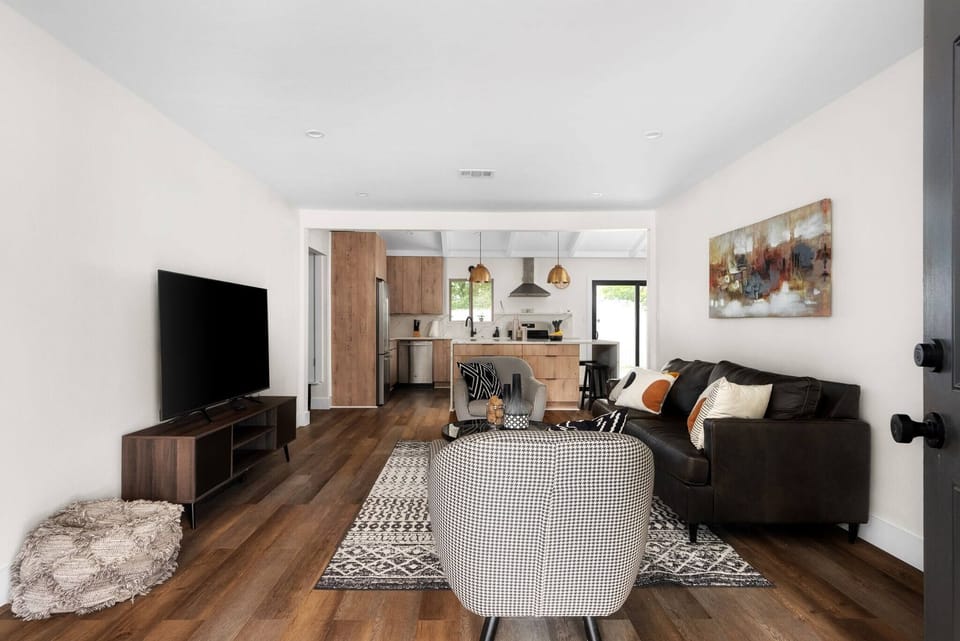 Open-concept living with a cozy lounge and large TV that flows seamlessly into the modern kitchen — perfect for relaxing, cooking, and spending time together