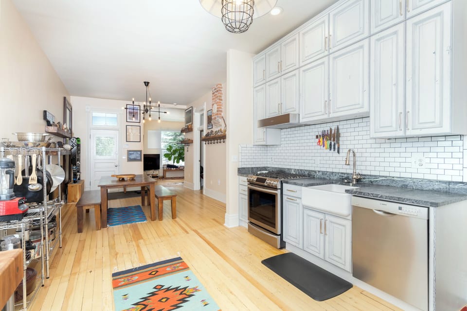 A view of the kitchen with stainless steel appliances, and a metal shelf holding pots and pans.