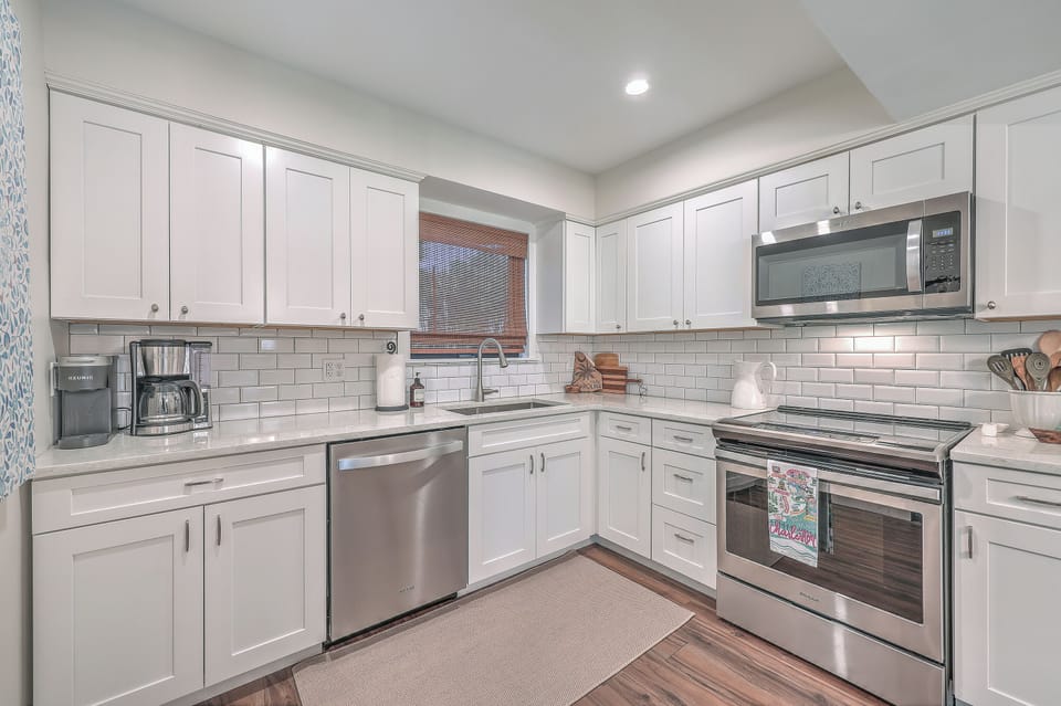 Cook with ease in the modern kitchen, featuring pristine white cabinetry, subway tile backsplash, and stainless steel appliances.