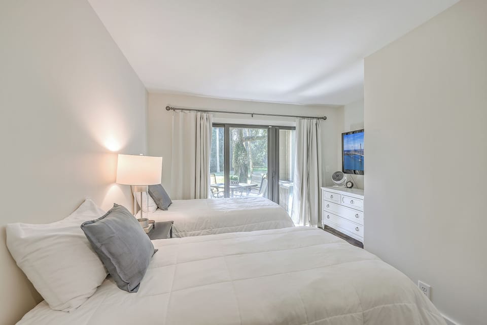The cozy second bedroom features two comfortable twin beds and direct access to the outdoor patio.