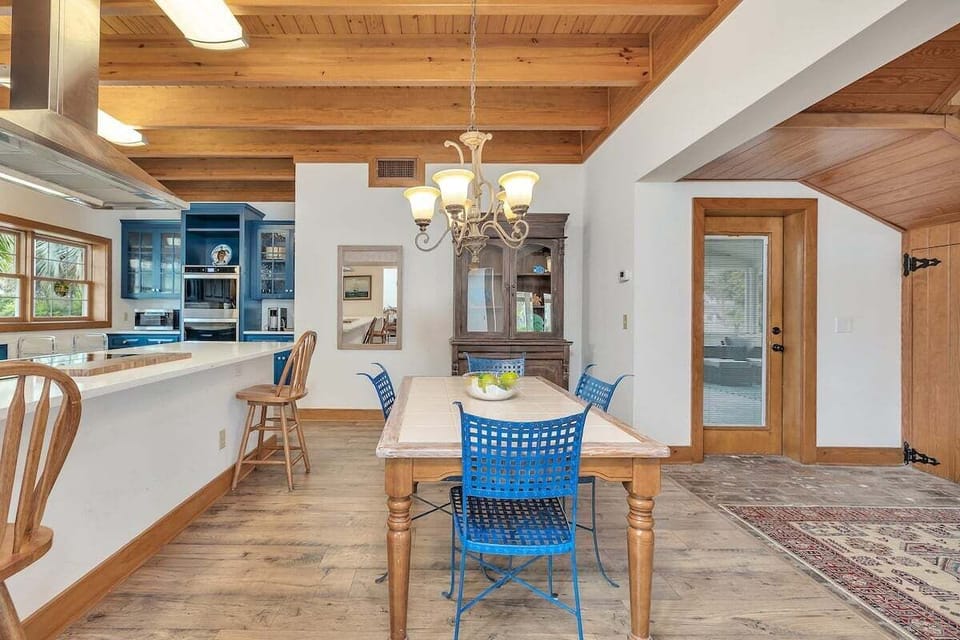 Open dining room with wood ceiling and blue kitchen view