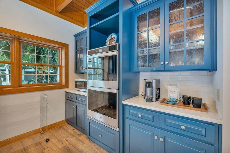 Blue cabinets with stainless range and wood-framed window