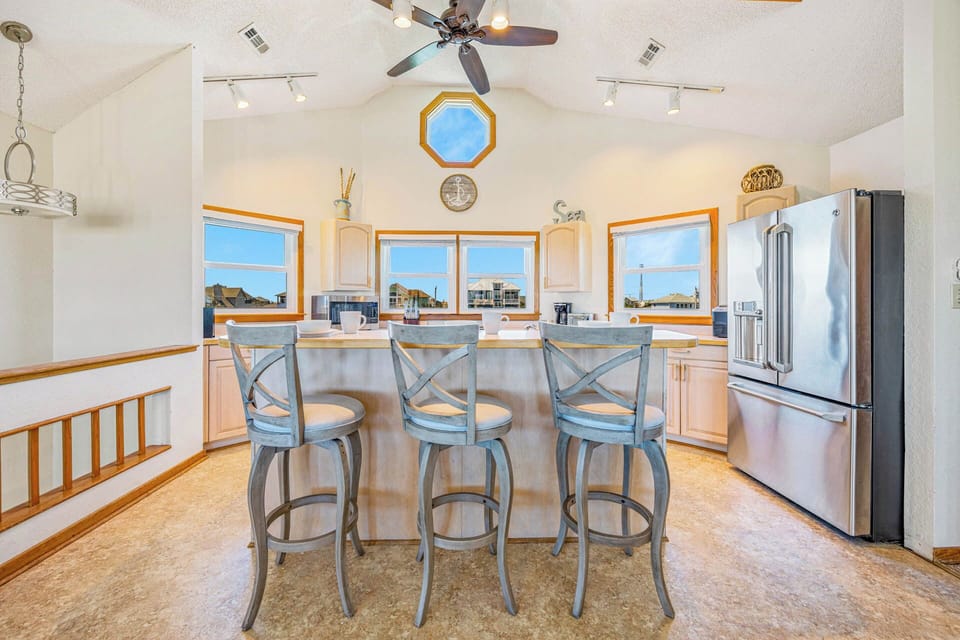 Your sunlit kitchen features a welcoming breakfast bar and sweeping views through bright windows, with vaulted ceilings and sleek stainless appliances making every meal feel special.