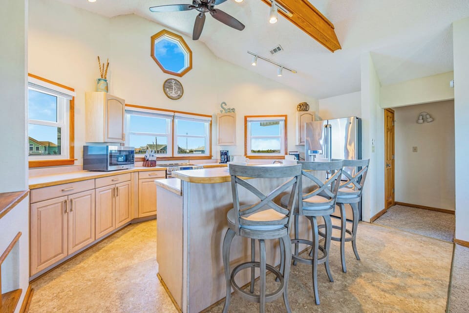 Gather at the breakfast bar in your sunlit kitchen, where vaulted ceilings and coastal décor create a breezy space for morning coffee or evening wine.