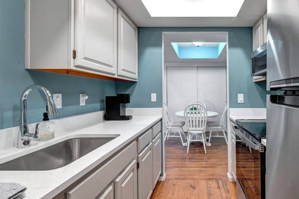 Modern kitchen with sleek countertops, stainless appliances, and a sunny breakfast nook just beyond—your perfect spot for morning coffee and meal prep.