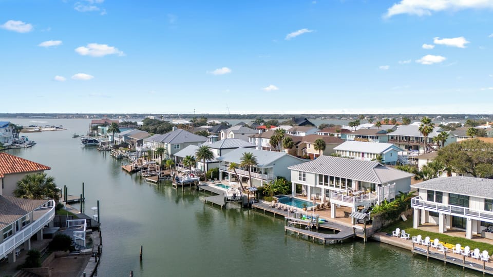 Aerial view of home, pool, dock & scenic canal-front setting.