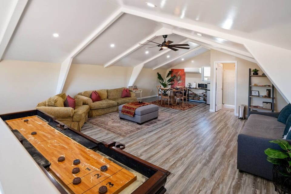 Barndominium loft with shuffleboard, cozy lounge, day bed, and full bathroom at River Road Retreat.