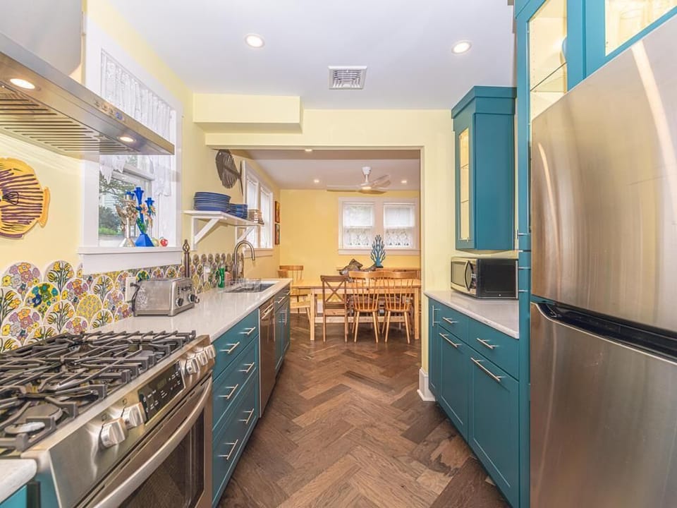 Fully equipped kitchen with vibrant cabinetry, stainless steel appliances, and eye-catching backsplash – perfect for preparing meals during your stay.