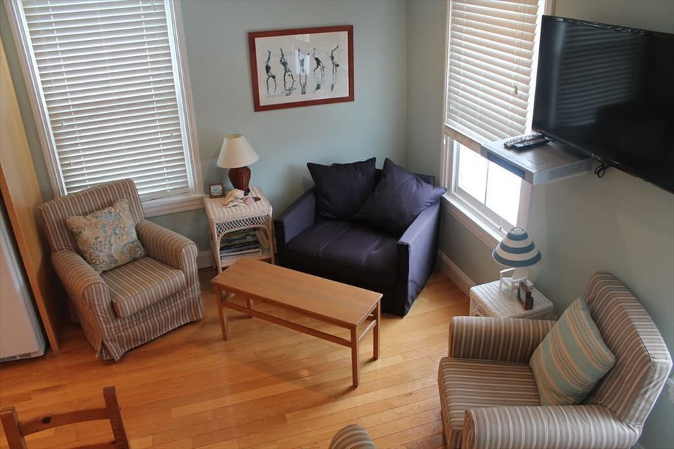 Cozy living space with plenty of seating, natural light, and a mounted TV for entertainment.