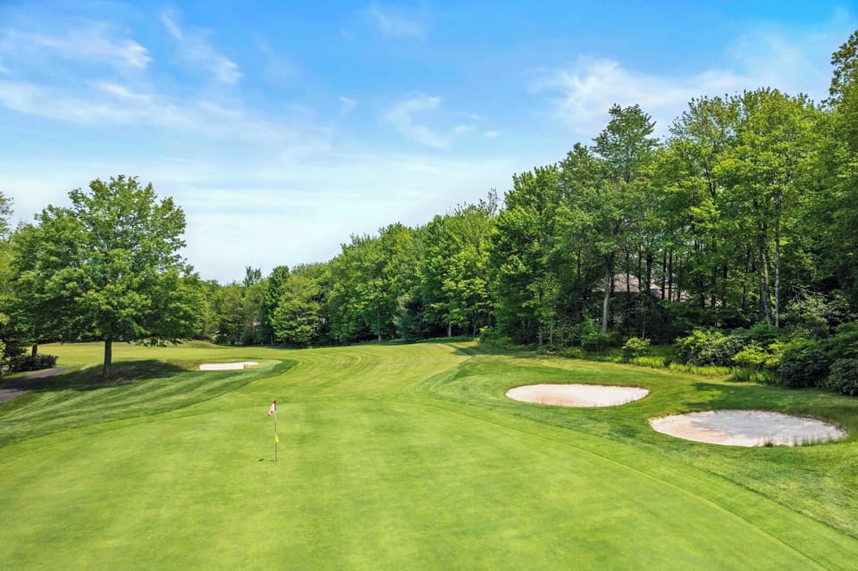 Picture your round at the neighboring course - a green, flag, and bunkers framed by mature trees.  