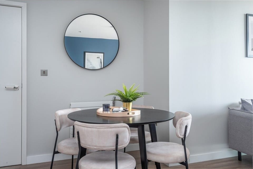 Chic dining nook with round table, statement mirror and fresh greenery