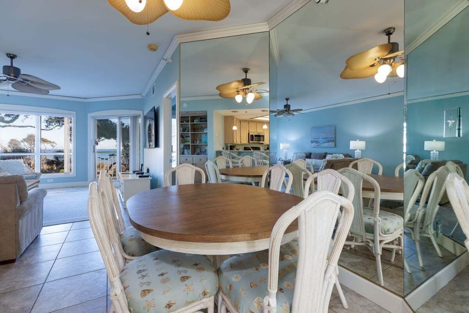 Soft coastal colors, mirrored walls, and warm lighting create an open, airy feel that flows seamlessly into the kitchen and living spaces.