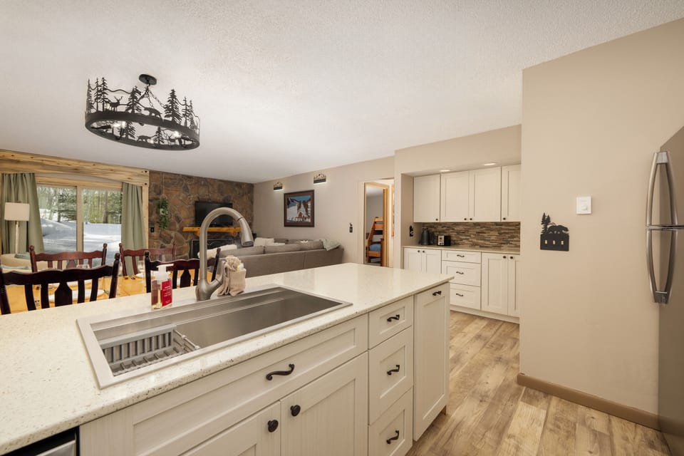 Cook with ease in this spacious open kitchen featuring granite countertops, modern appliances, and charming rustic chandelier overhead.
