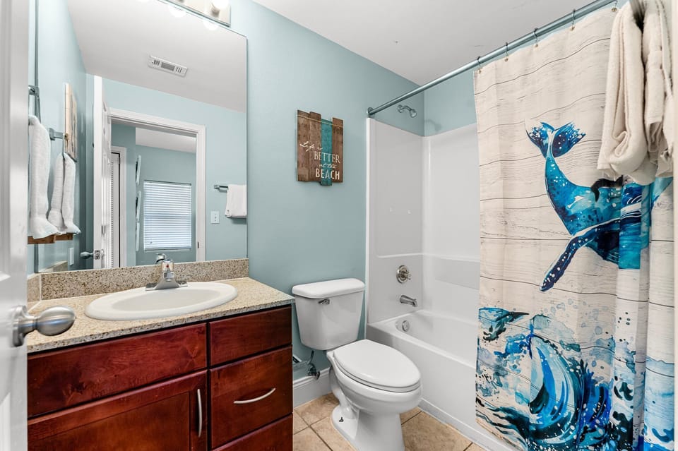 Bathroom with a dolphin-themed shower curtain and light blue walls.