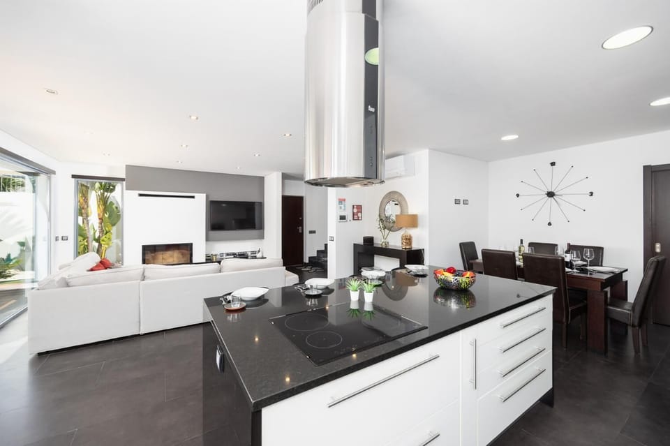 Open-plan living room with sofa, dining area, kitchen, ornamental fireplace, A/C, WiFi internet, and satellite TV