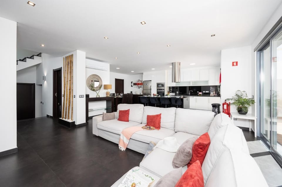 Open-plan living room with sofa, dining area, kitchen, ornamental fireplace, A/C, WiFi internet, and satellite TV