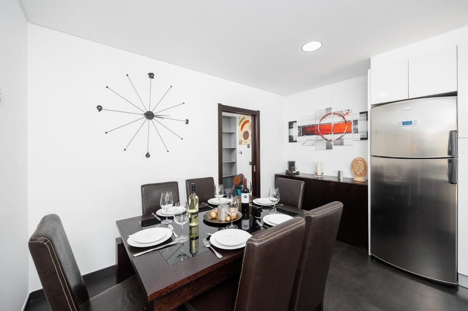 Open-plan living room with sofa, dining area, kitchen, ornamental fireplace, A/C, WiFi internet, and satellite TV