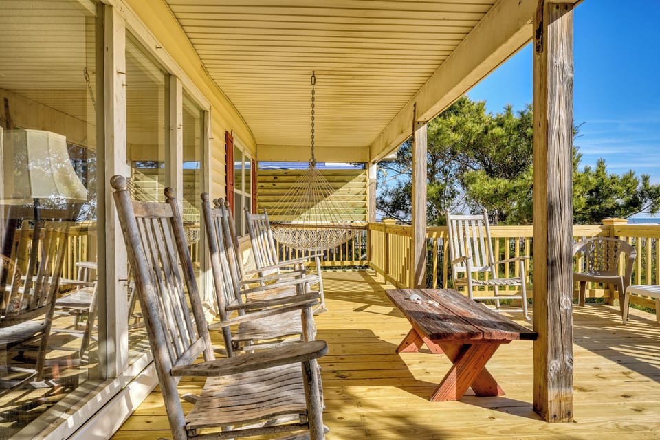 A porch full of rocking chairs has a shady awning to keep out of the sun. 