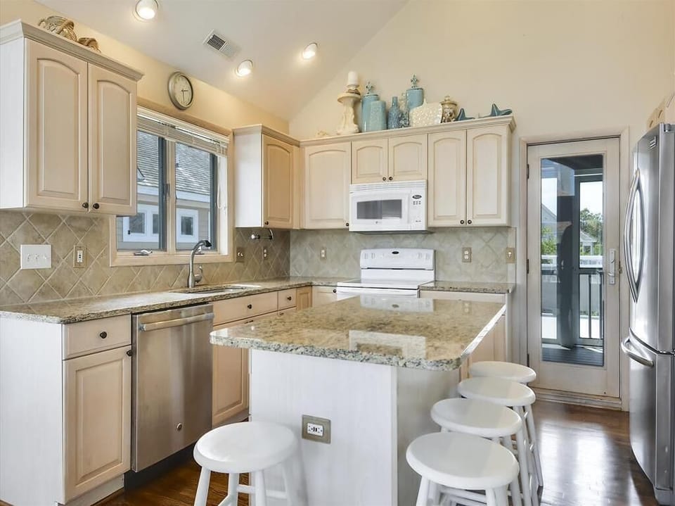 Bright and fully equipped kitchen with modern appliances, granite countertops, and a breakfast bar, perfect for preparing meals with family or friends.