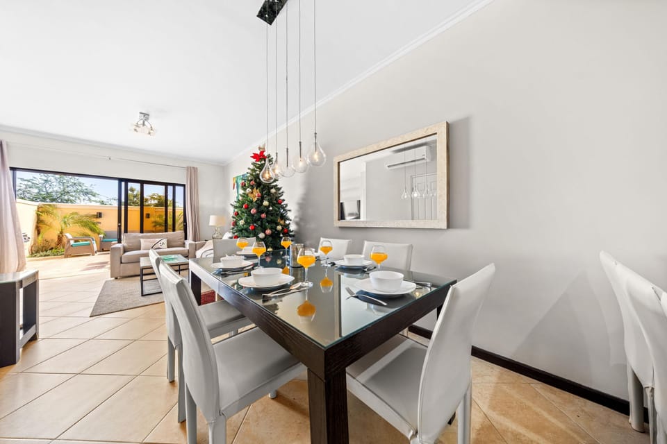 Glass-topped table, set for a meal, linking the living room and dining area with views of the patio.