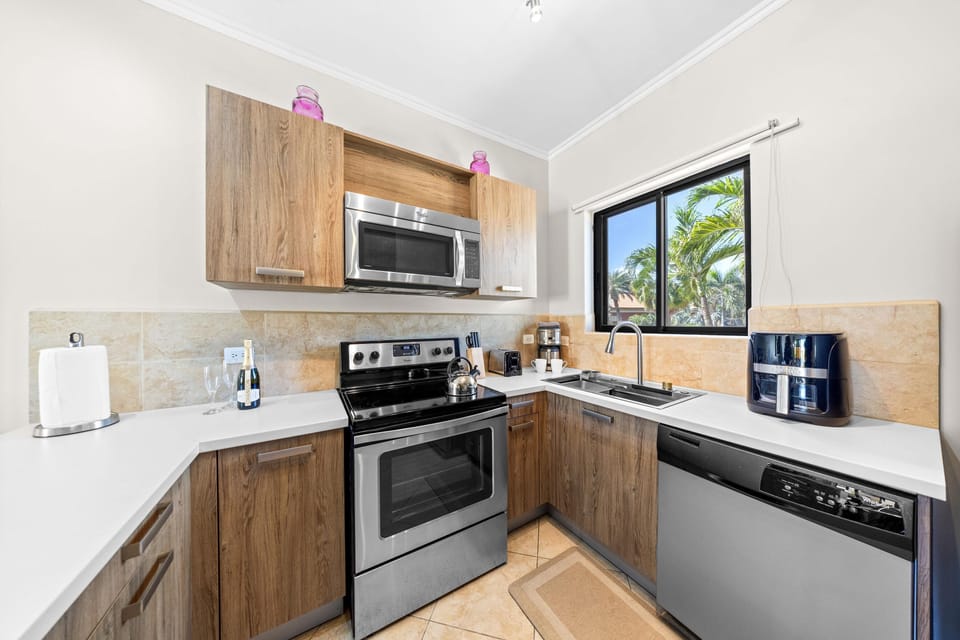 A spacious kitchen with a view, featuring a corner layout, stainless steel appliances, and an air fryer for added convenience.