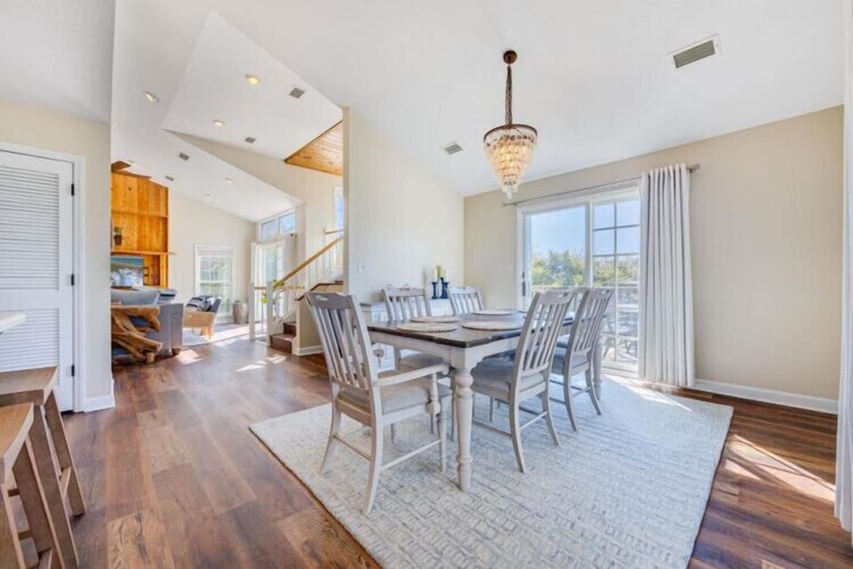Step into this bright, open dining space where vaulted ceilings and an elegant chandelier set the stage for your family meals. Natural light pours through large windows, warming the polished wood floors beneath your feet.