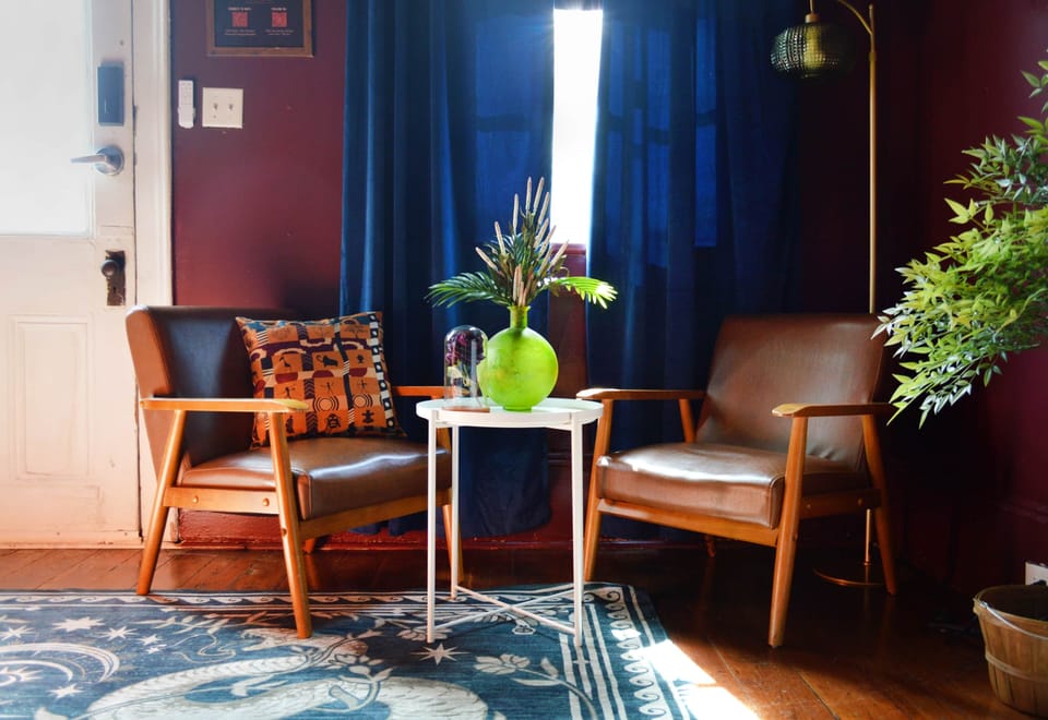 Sunlit reading nook with mid-century chairs and vintage décor inside this historic New  Orleans home
