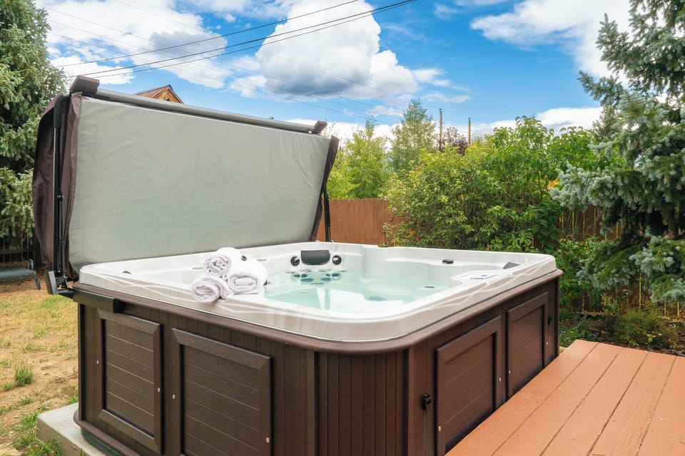 Slip into your private hot tub oasis, complete with fluffy towels, surrounded by lush greenery for ultimate relaxation.
