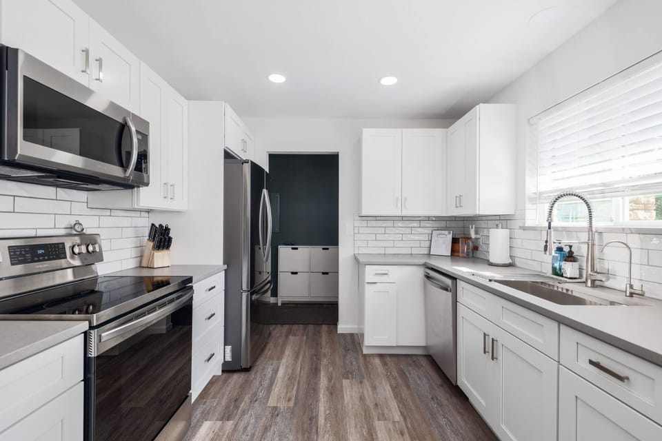 Cook and socialize in the roomy kitchen, featuring a stove, oven, and plenty of counter space on one side, with a convenient sink on the other—ideal for meal prep and entertaining.