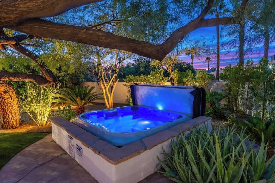 Sink into the glowing hot tub beneath mature trees and a stunning twilight sky—your perfect end to each evening in this lush, private garden oasis.