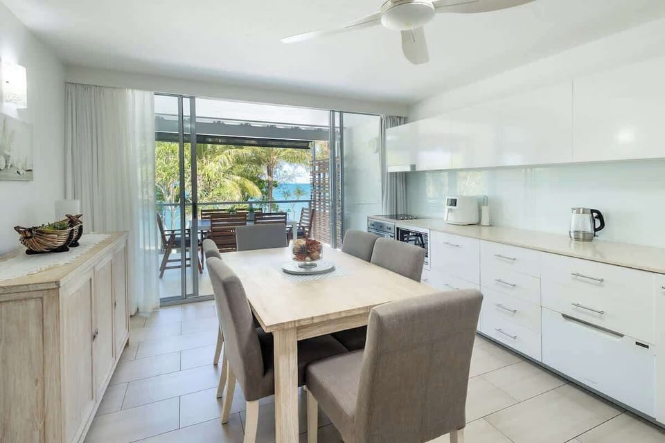 Gather around the six-seater dining table for long breakfasts and relaxed evening meals, with the fully equipped kitchen and balcony just steps away for effortless indoor-outdoor living.