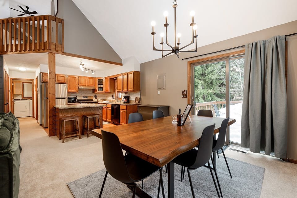 Dining area w/ large table, chandelier & sliding doors to the deck