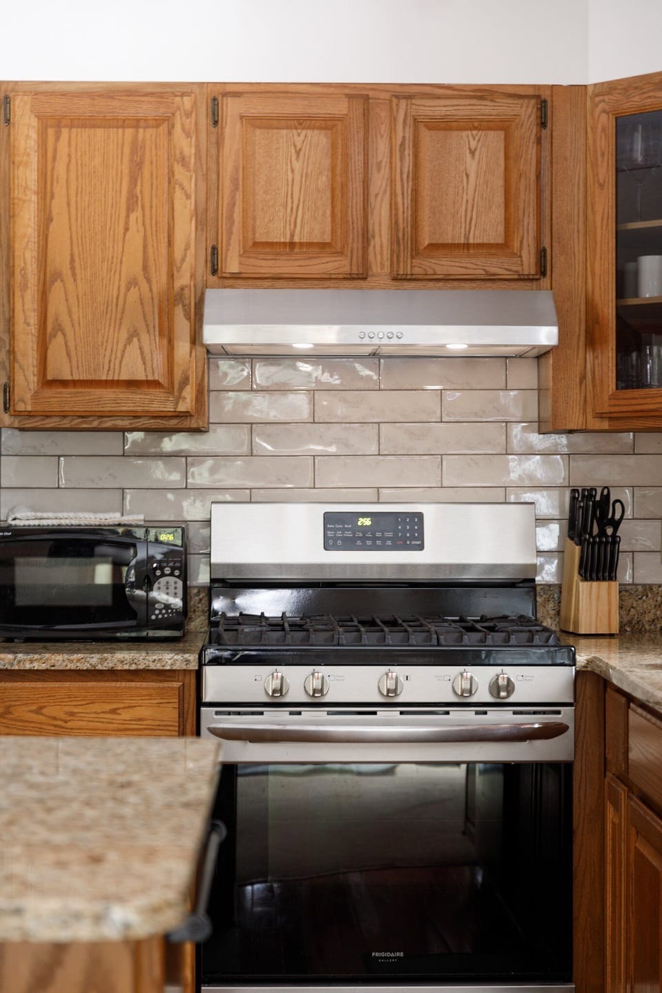 Close-up of the kitchen range w/ tile backsplash & vent hood detail