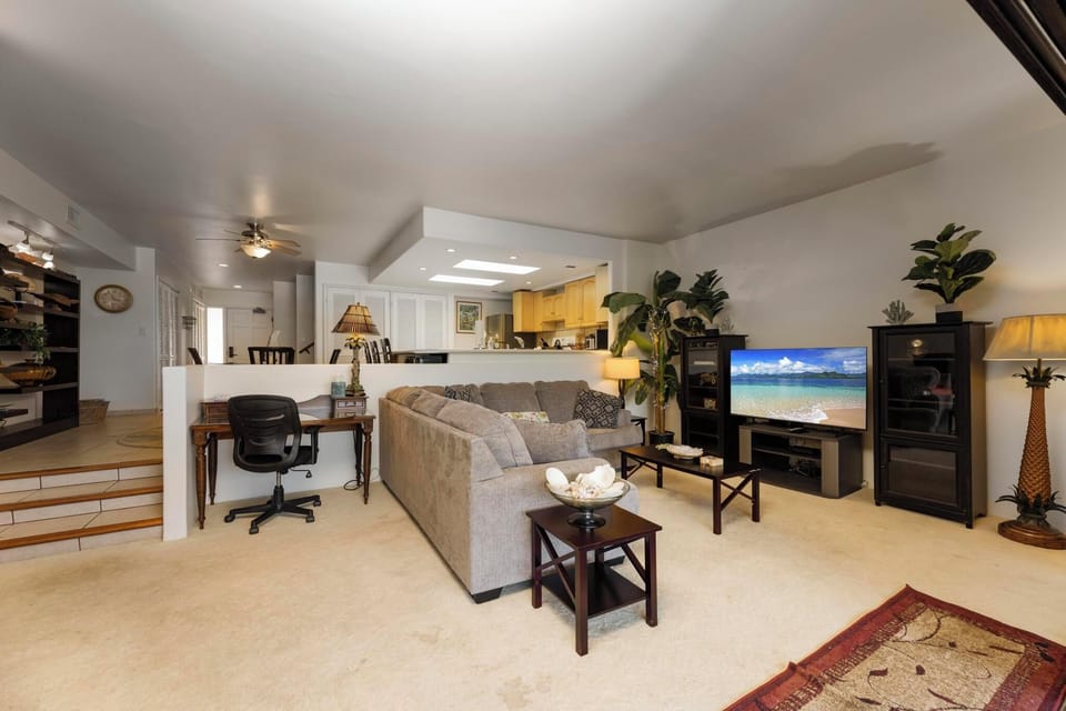 Unwind in the bright and cozy living room featuring a large flat-screen TV and comfortable seating, perfect for family movie nights.