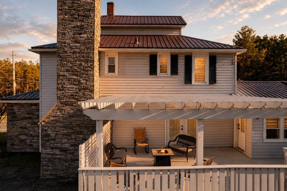 Warm up around the gas fire table on the deck, wicker chairs and a loveseat arranged for easy conversation. The stone chimney and covered pergola overhead make this a shaded spot any time of day.