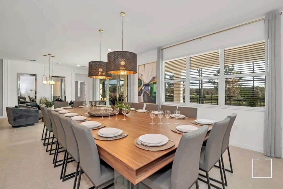 Spacious dining room with elegant seating for 12, perfect for gatherings, enhanced by natural light and stylish decor.