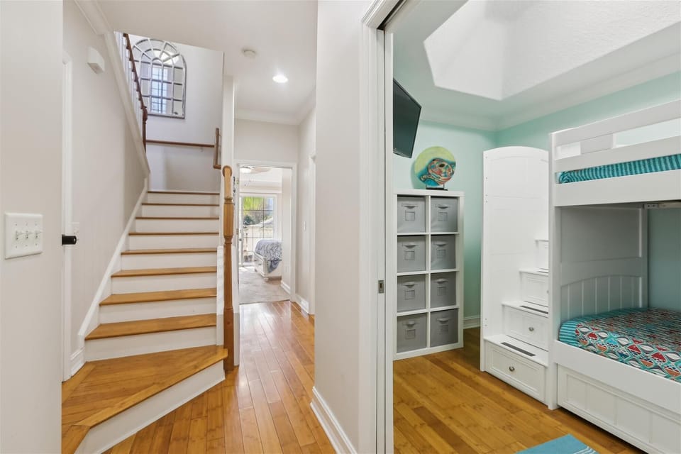 - Stairway view leading up with bunk bedroom in sight for added guest comfort  
- Hardwood floors bright walls and natural light create a warm beachy feel  
- Perfect for families with kids or groups sharing vacation rental space 