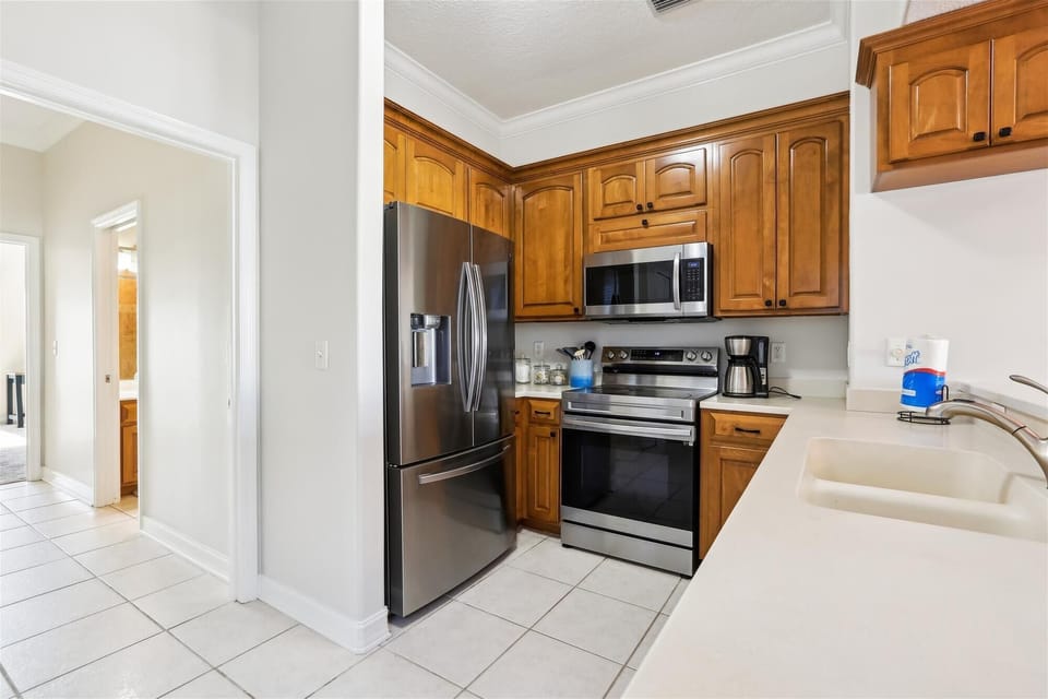 - Kitchen with refrigerator oven microwave and wood cabinets offering storage  
- Bright lighting and tile flooring create a clean practical space for cooking  
- Ideal for families preparing meals while enjoying their coastal getaway