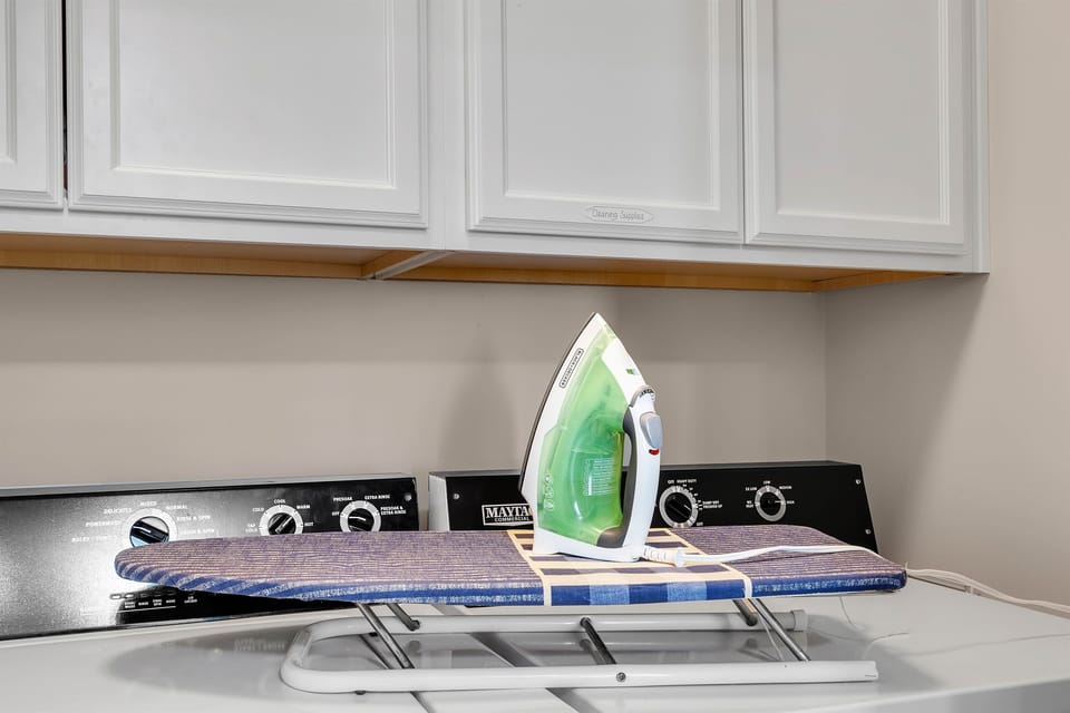 A convenient laundry room equipped with a washer, dryer, and an iron with ironing board for guest use.