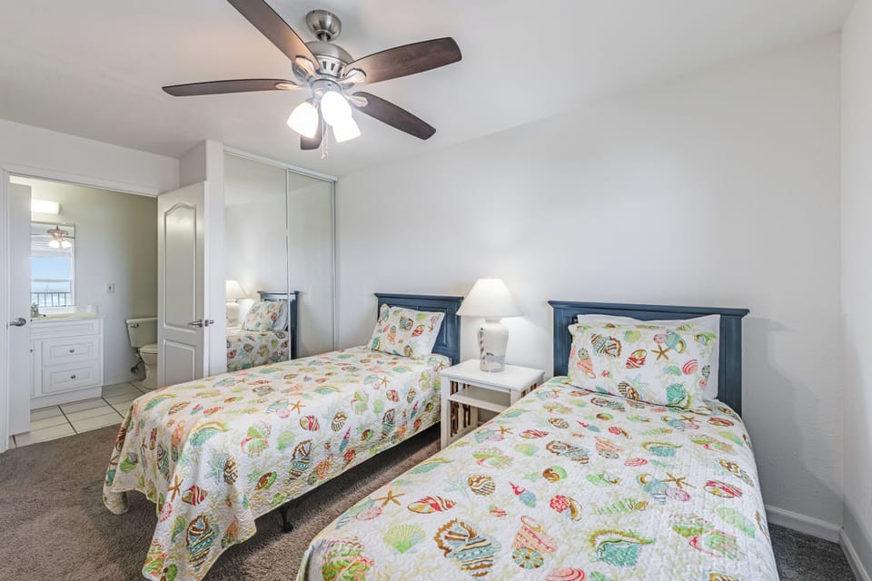 Rest comfortably in your twin bedroom with cheerful coastal bedding, ceiling fan for cool nights, and glimpses of ocean views.