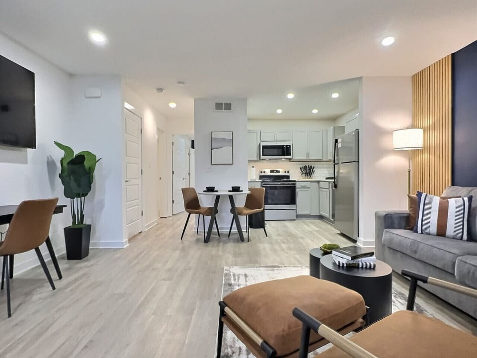 Bright and airy living area in this furnished apartment with comfortable seating, a TV, and a workspace, perfect for relaxing or staying productive.